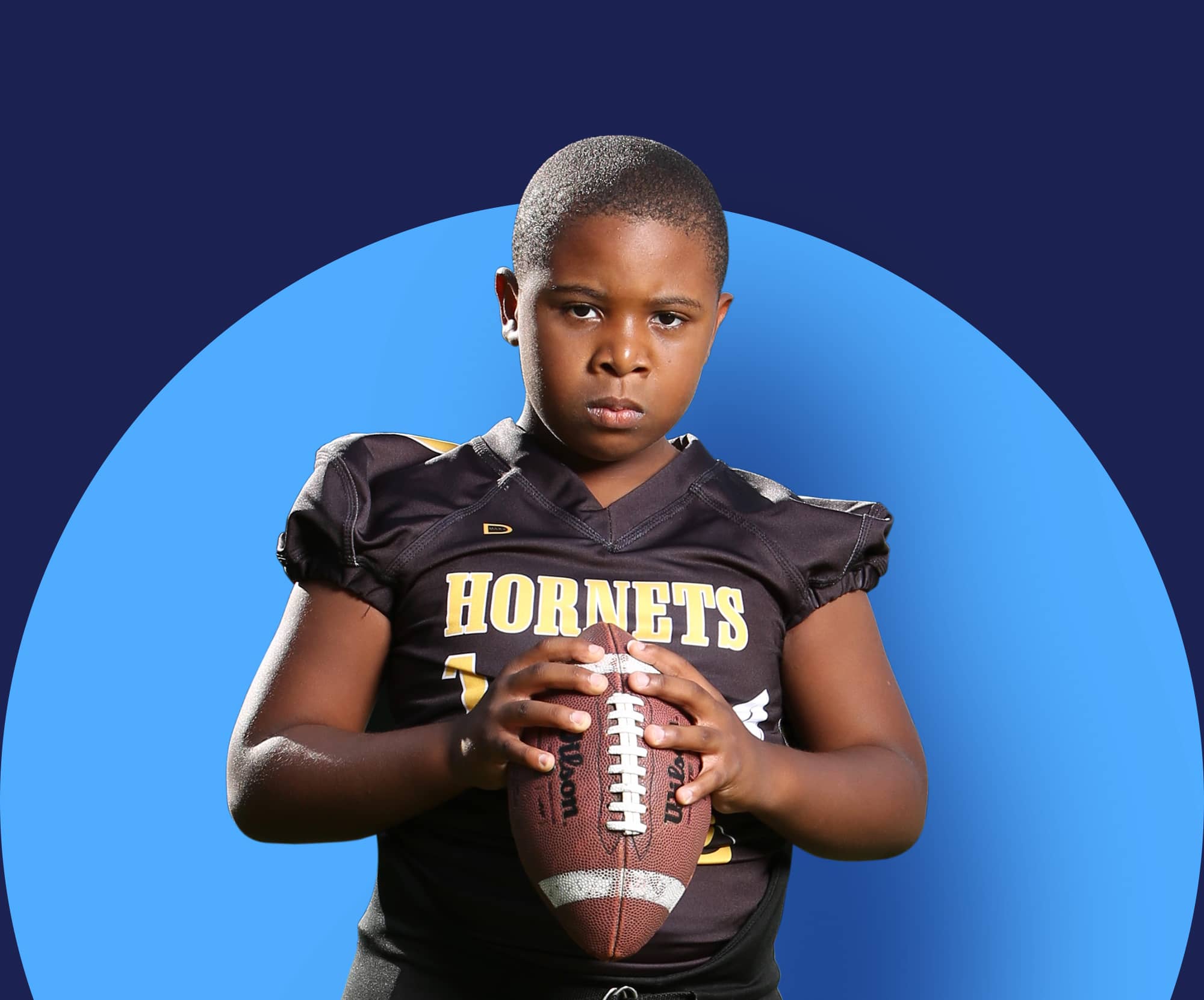 A boy holding a football during sports photoshoot day