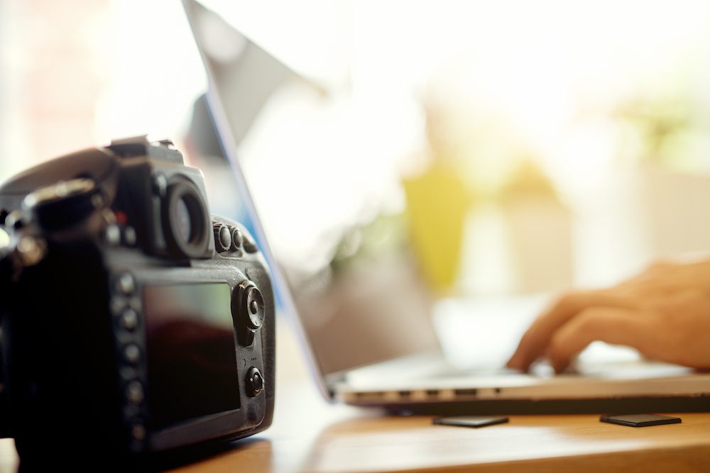 Photographer retouching photos on his computer. Work in progress after a successful photo shooting.