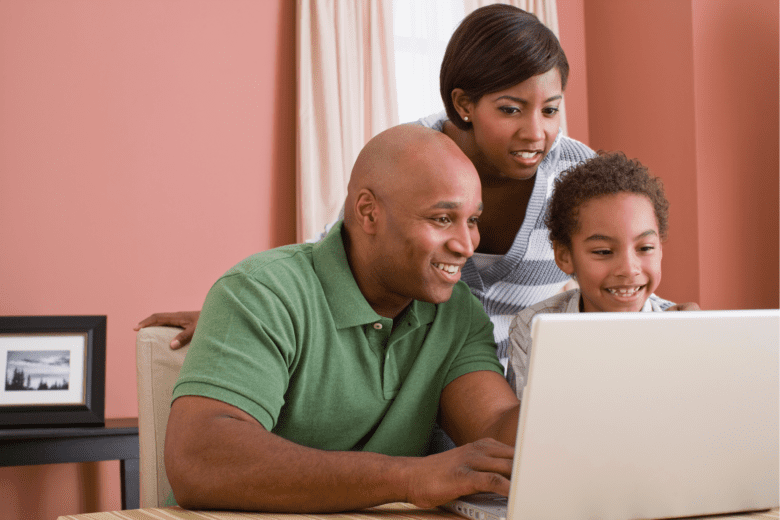 Parents and child smiling and looking at computer