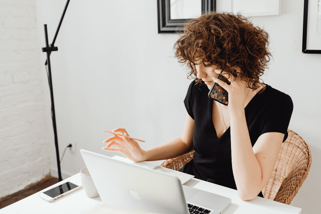 Woman on a call while using a laptop, emphasizing cold calling and communication for school photography.