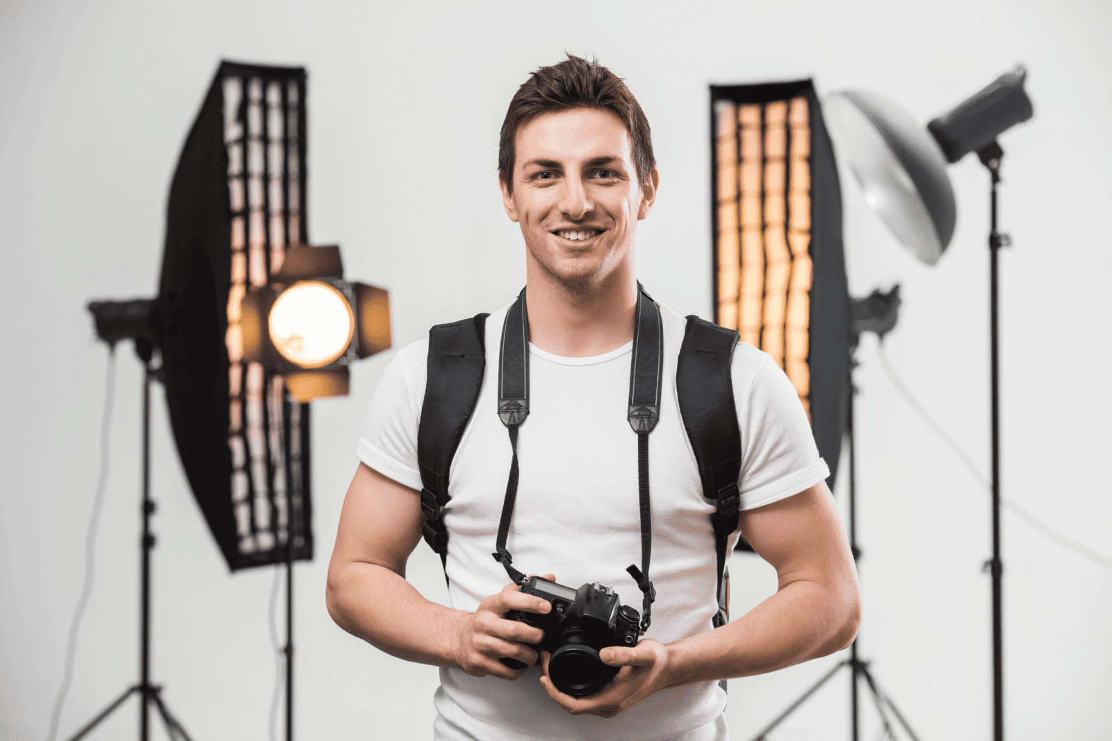 A photographer stands with his camera in front of lighting equipment