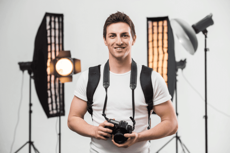 A photographer stands with his camera in front of lighting equipment