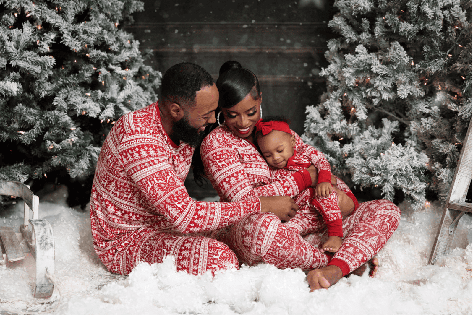 Family posing and smiling together in front of the Christmas tree