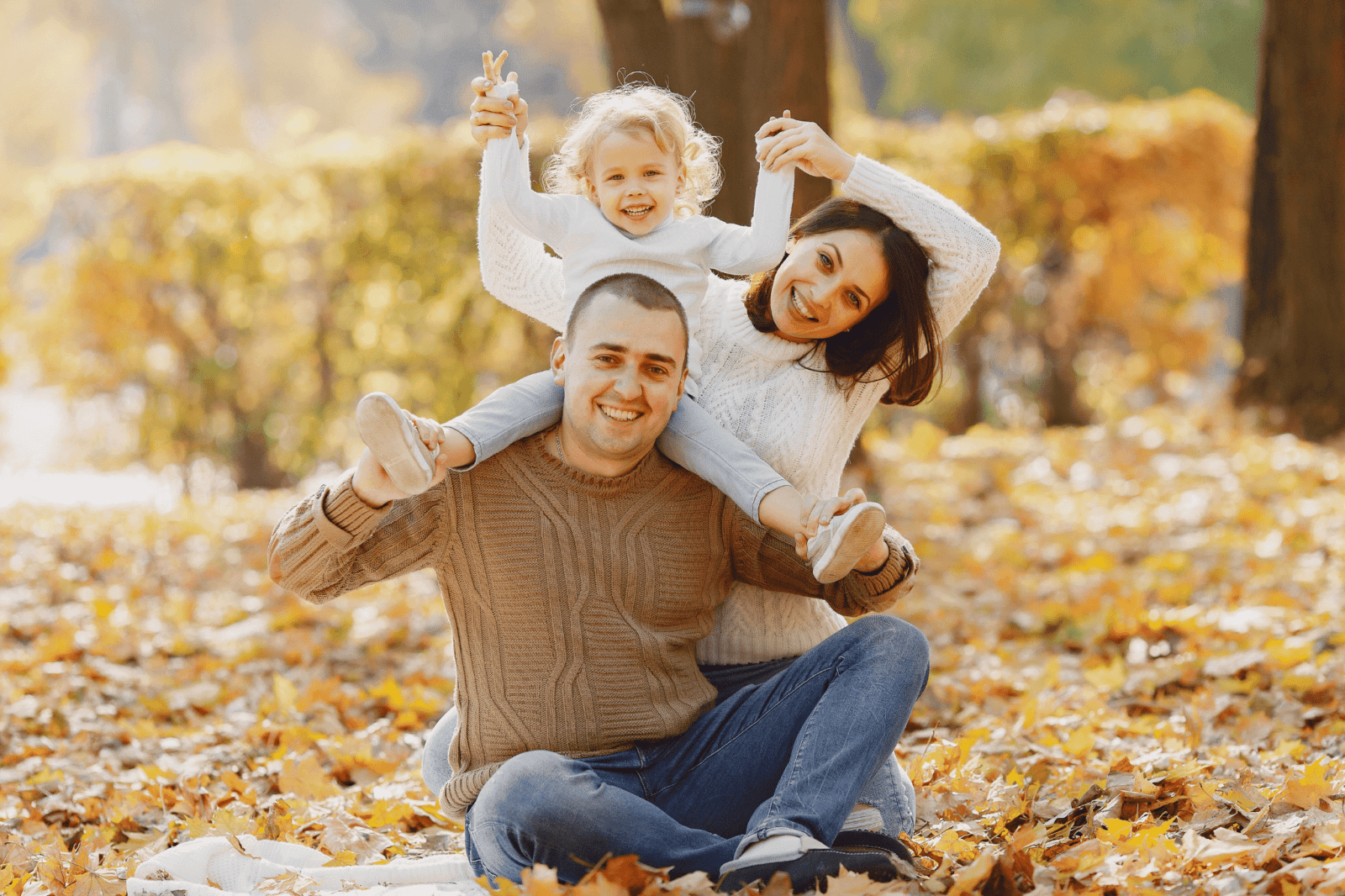 A family poses outside in fall leaves