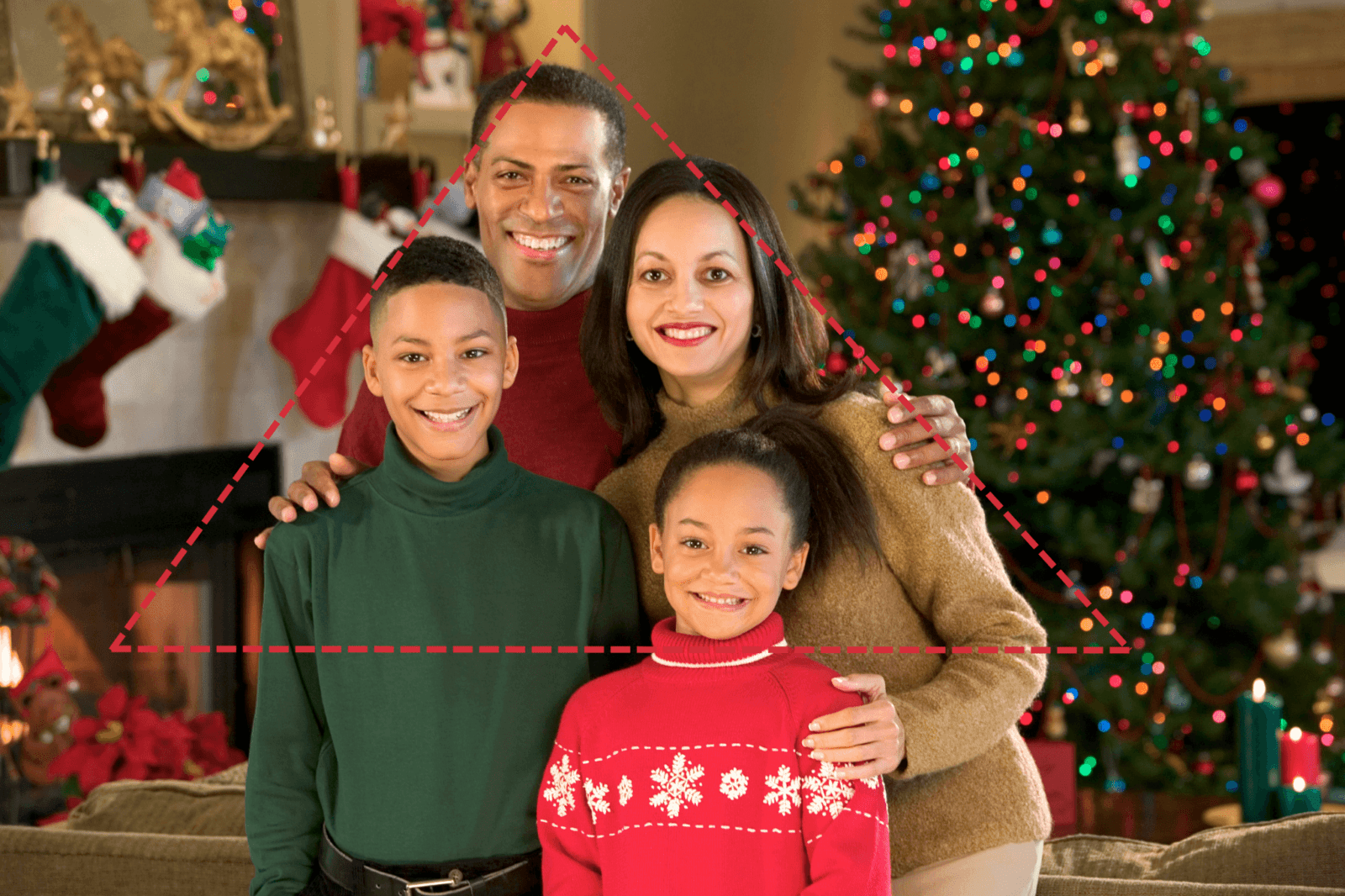 Family of four in a triangle pose in front of a Christmas tree