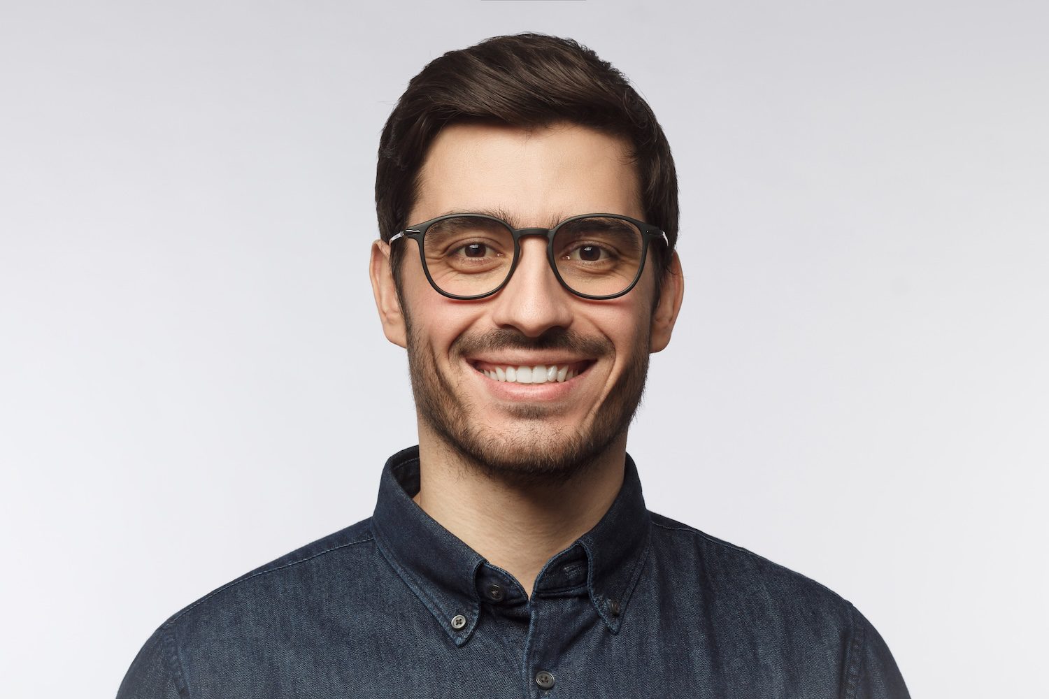 Portrait of young smiling man in denim shirt isolated on gray background