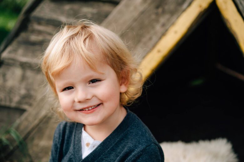 A young boy in preschool or kindergarten smiles for his school picture