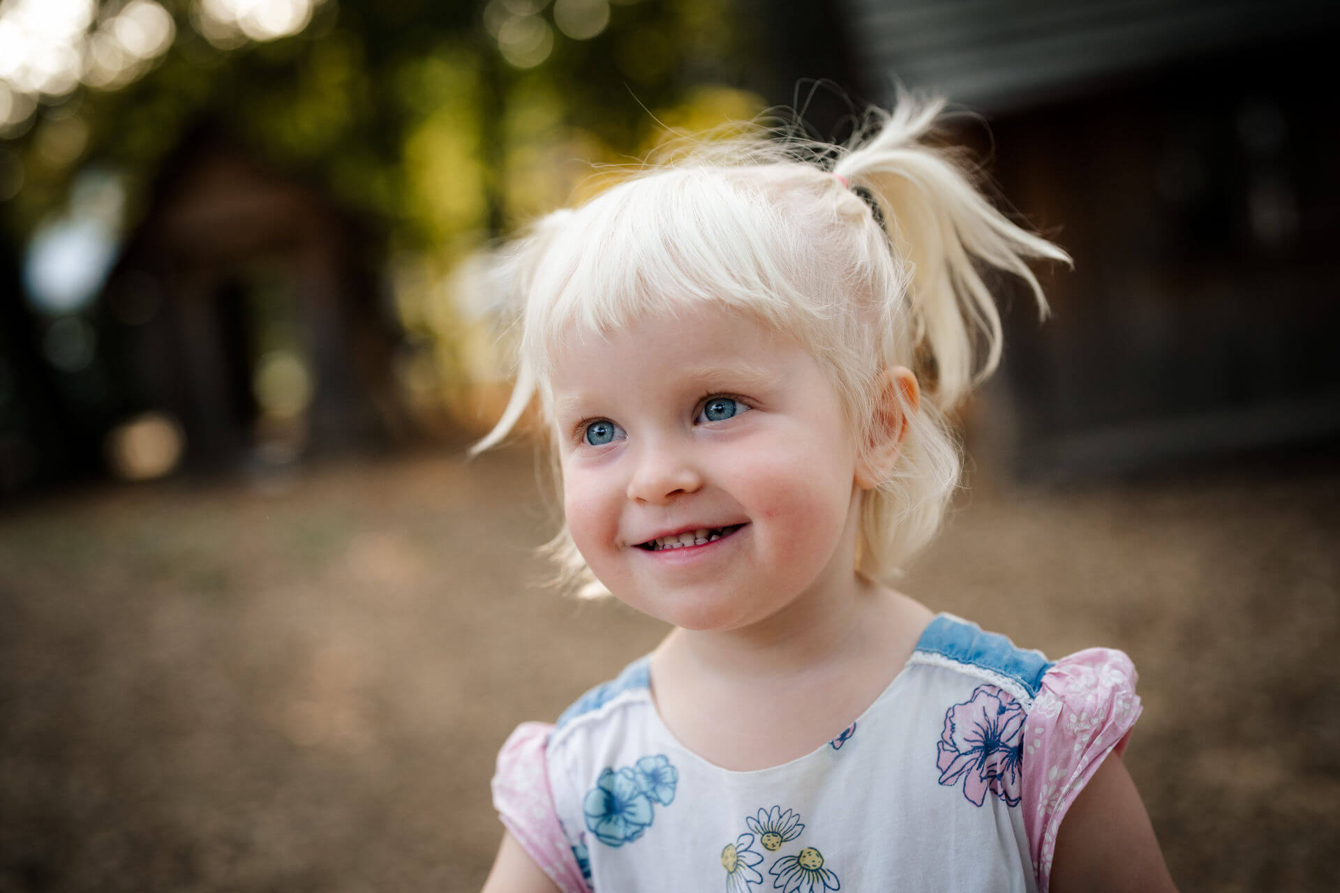 A preschool-age girl smiles for a picture outside