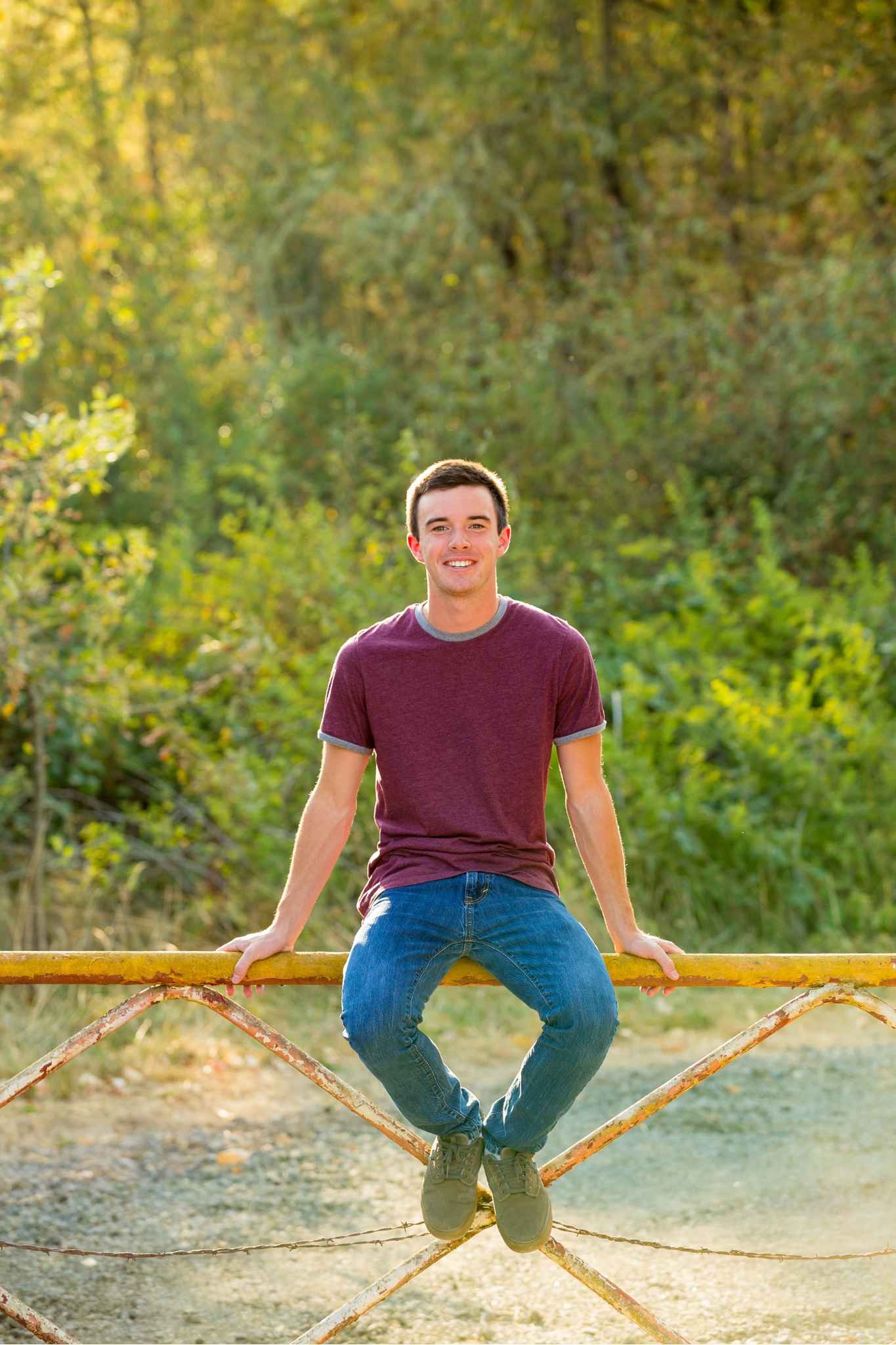 A high school senior poses on a bridge over a river