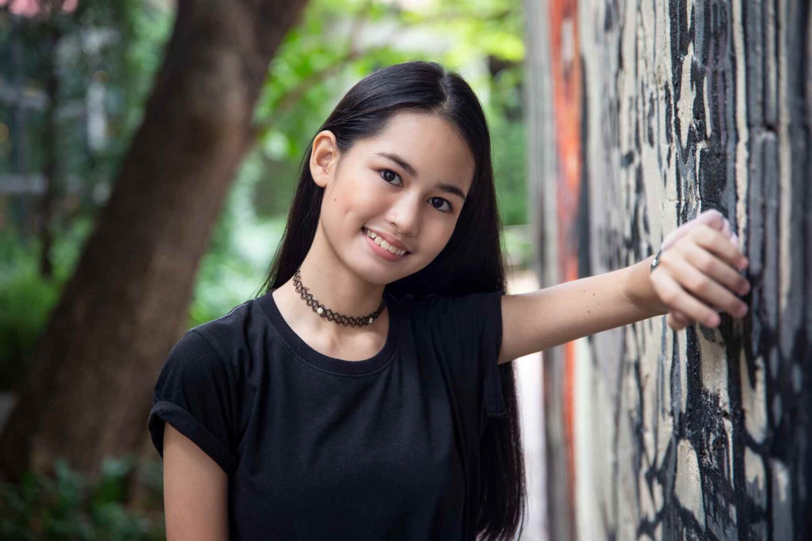 A woman leans against a wall outside in her portrait demonstrating choosing the right location