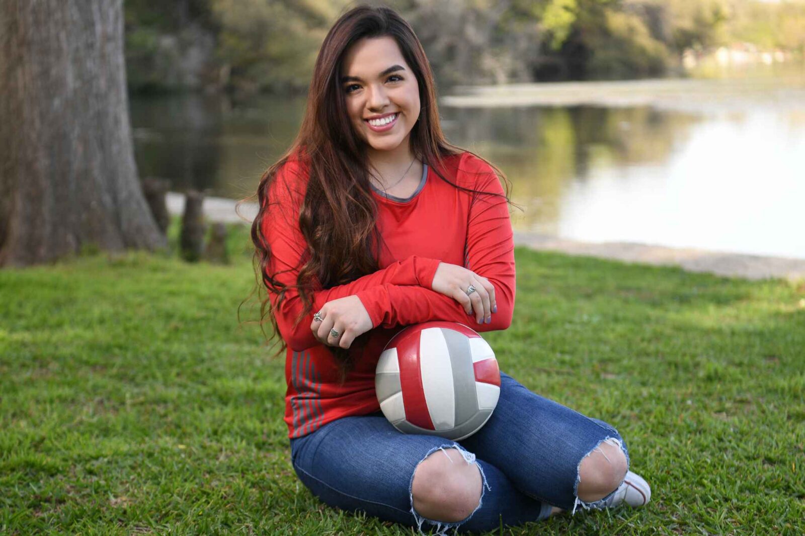 A high school senior poses with her volleyball in a senior portrait