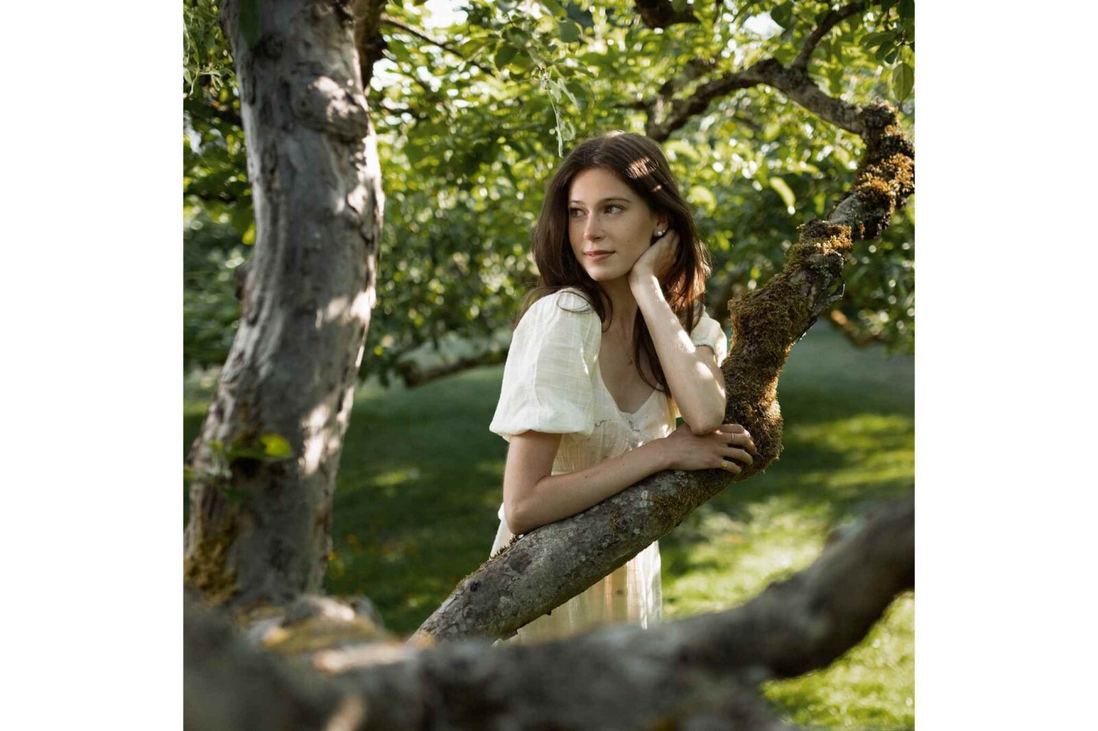 A woman poses outdoor surrounded by trees for framing