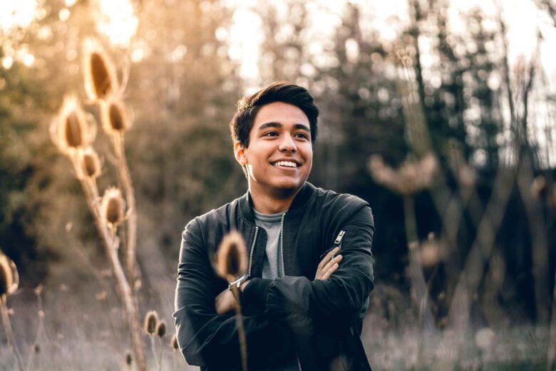 A man poses in a field demonstrating natural lighting and golden hour for outdoor portraits